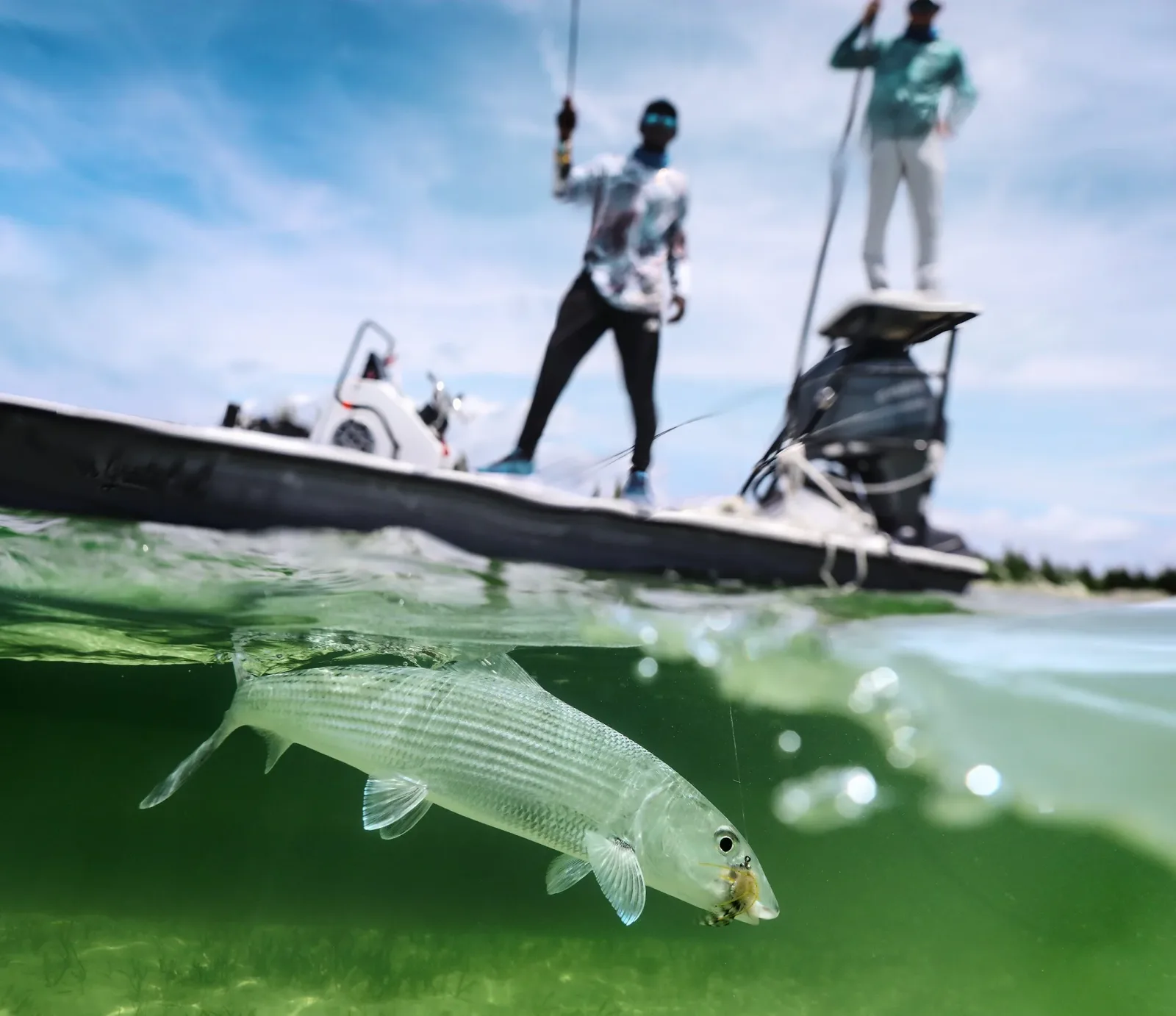 Two Privateers Bahamas fishing guides poling a flats skiff while a client fly-fishes in shallow turquoise water